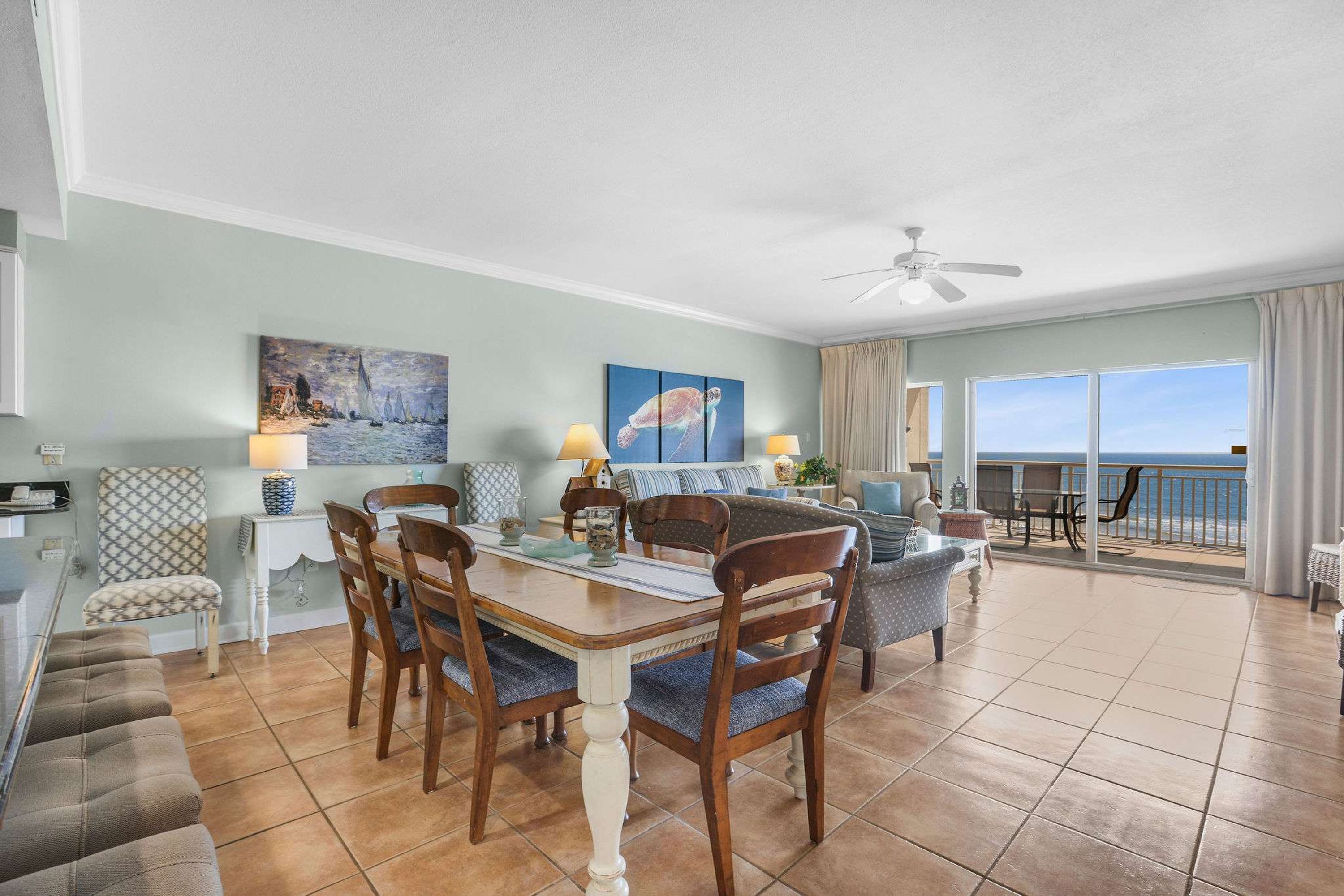 Un coin repas avec une table et des chaises, un canapé et une vue sur l’océan grâce à de grandes fenêtres.