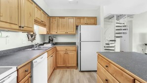 A modern kitchen with wooden cabinets, a white refrigerator, and a built-in dishwasher.