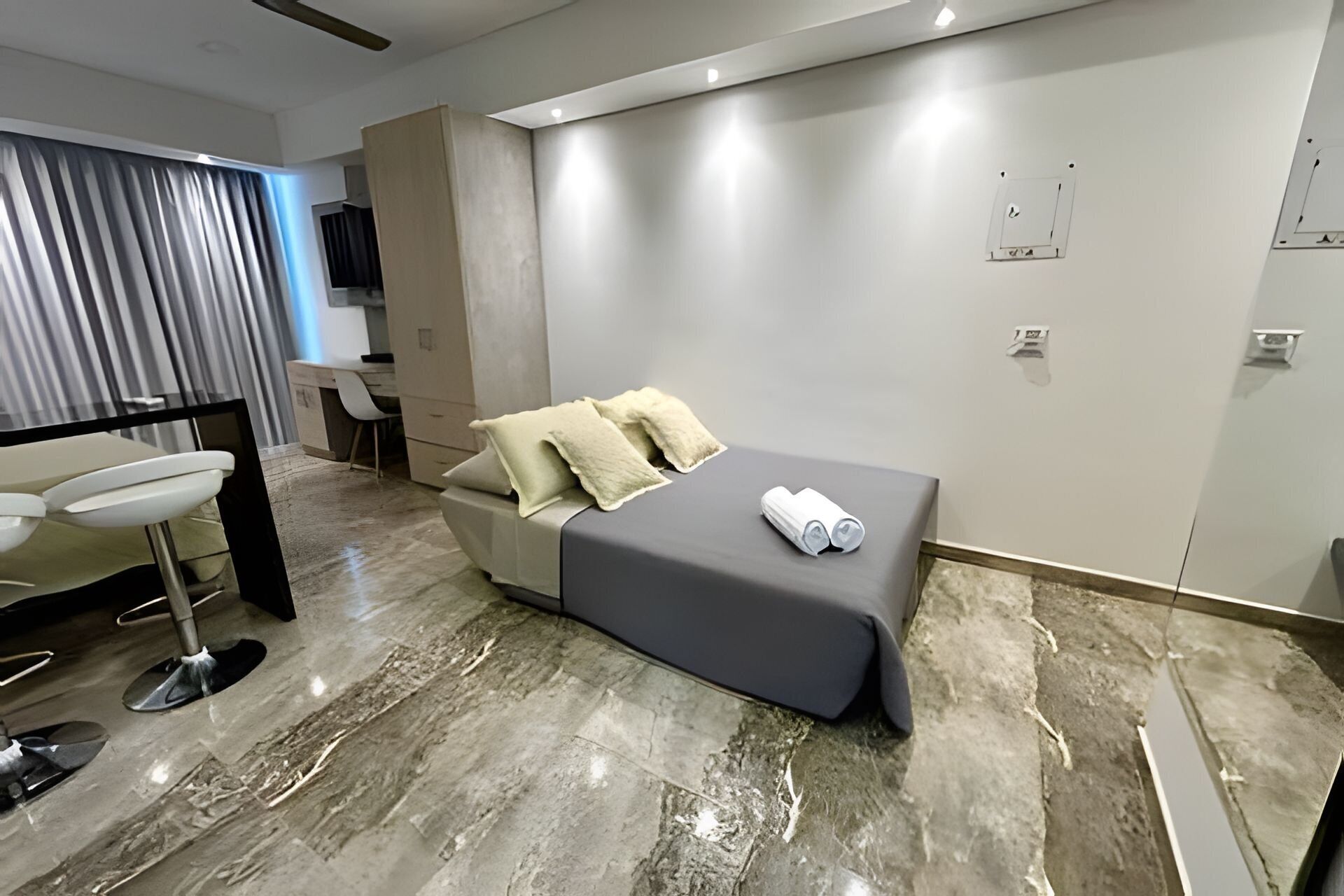 A modern hotel room with a bed, a desk, and a chair.