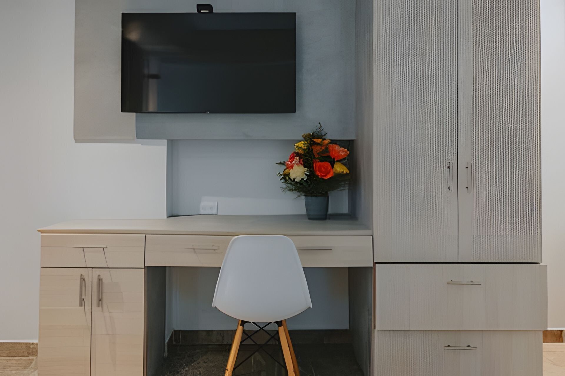 Un espacio de oficina moderno con un escritorio, una silla, un televisor y un armario.