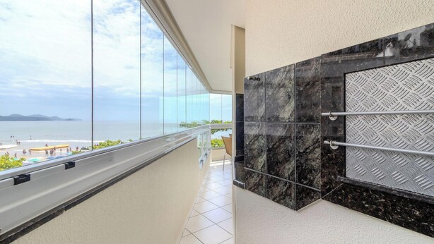 A balcony with a view of the sea and beach, a tiled floor, and a metal railing. - 3BR Seafront apt w/ BBQ in Itapema Con0101 (Itapema)