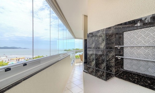 A balcony with a view of the sea and beach, a tiled floor, and a metal railing. - 3BR Seafront apt w/ BBQ in Itapema Con0101 (Itapema)
