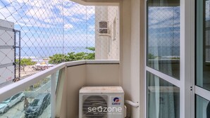 A balcony with a view of the sea, a white air conditioning unit, and a glass door. - 3BR Seafront apt w/ BBQ in Itapema Con0101 (Itapema)