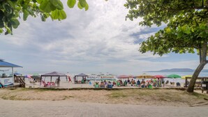 A beachside area with a food stall, umbrellas, and beach chairs. - 3BR Seafront apt w/ BBQ in Itapema Con0101 (Itapema)