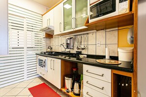 A kitchen with white cabinets, a stove, and a microwave.