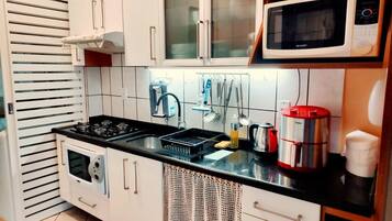 A compact kitchen with a gas stove, a microwave, and a coffee maker.