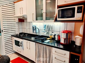 Una cocina compacta con estufa a gas, microondas y cafetera.