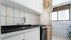 Eine moderne Küche mit weißen Schränken, einer schwarzen Arbeitsplatte und einem eingebauten Backofen.