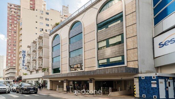 Een hotel met een moderne gevel, grote boogvensters en een zichtbaar bord met 'Hotel'.