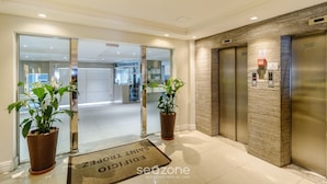 A hotel lobby with a reception desk, glass doors leading to a waiting area, and an elevator. - 3BR Beachfront apt w/ sea View Cet802 (Balneário Camboriú)