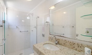 Une salle de bain moderne dotée d’une douche à parois de verre, d’un lavabo avec un plan de travail en marbre et d’un grand miroir.