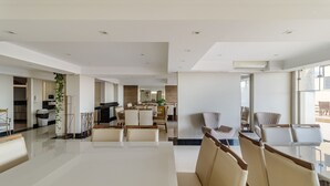 A spacious, modern living area with a large dining table, comfortable seating, and a kitchen in the background. - 3BR Beachfront apt w/ sea View Cet802 (Balneário Camboriú)