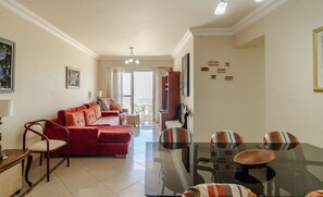 A modern living room with a glass dining table, red sofa, and striped chairs. - 3BR Beachfront apt w/ sea View Cet802 (Balneário Camboriú)
