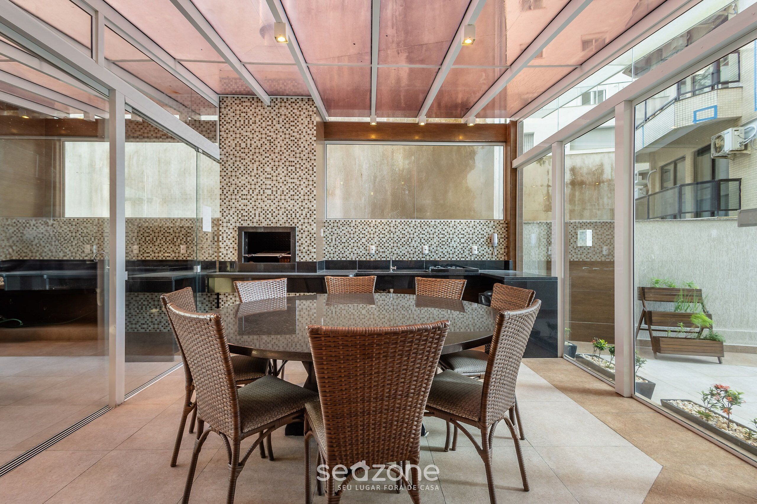 Una cocina moderna con una isla grande, puertas de vidrio y un comedor con sillas de mimbre.