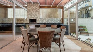 A modern kitchen with a large island, glass doors, and a dining area with wicker chairs.