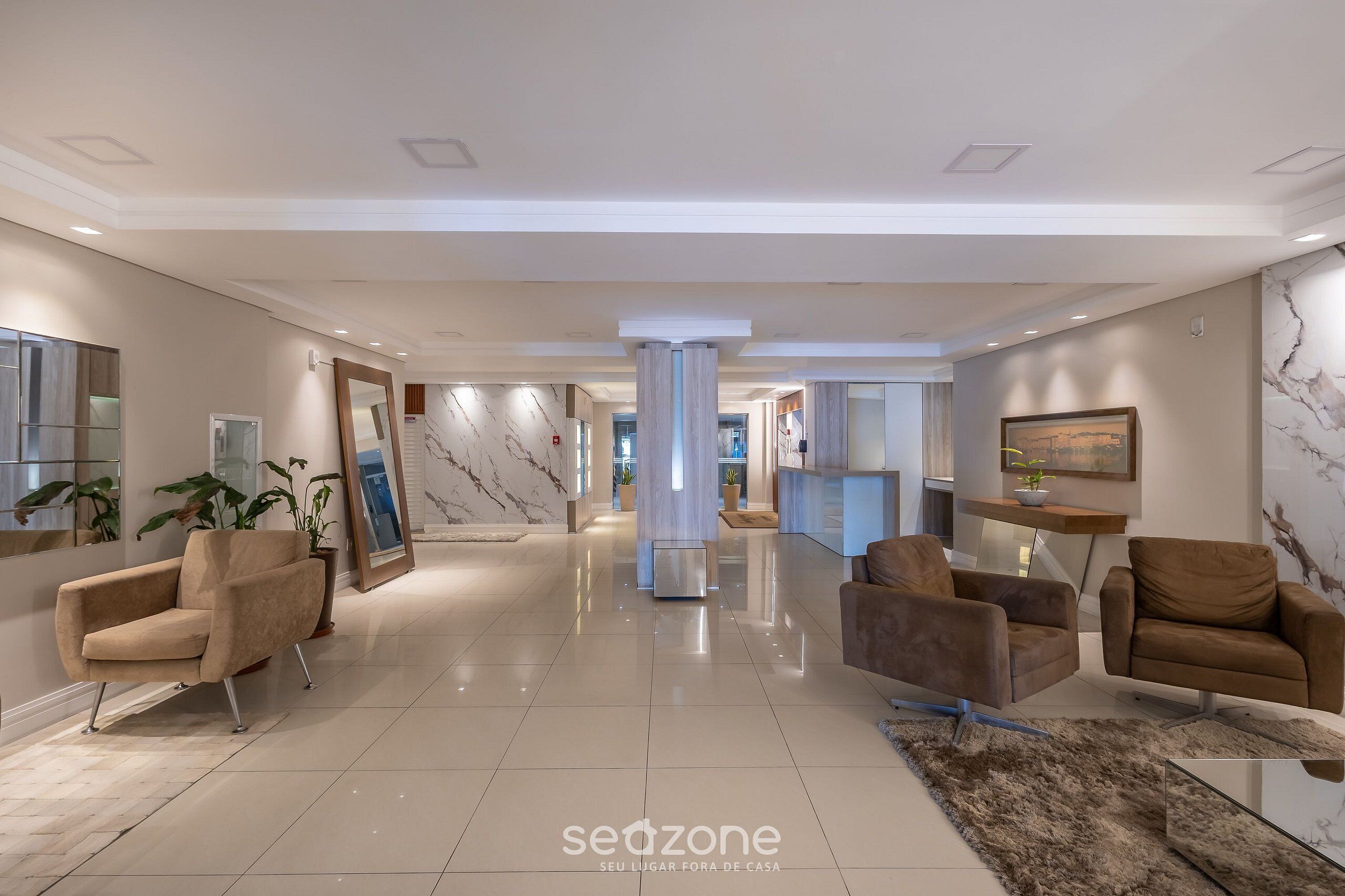 A spacious lobby with a marble floor, modern furniture, and a central column.