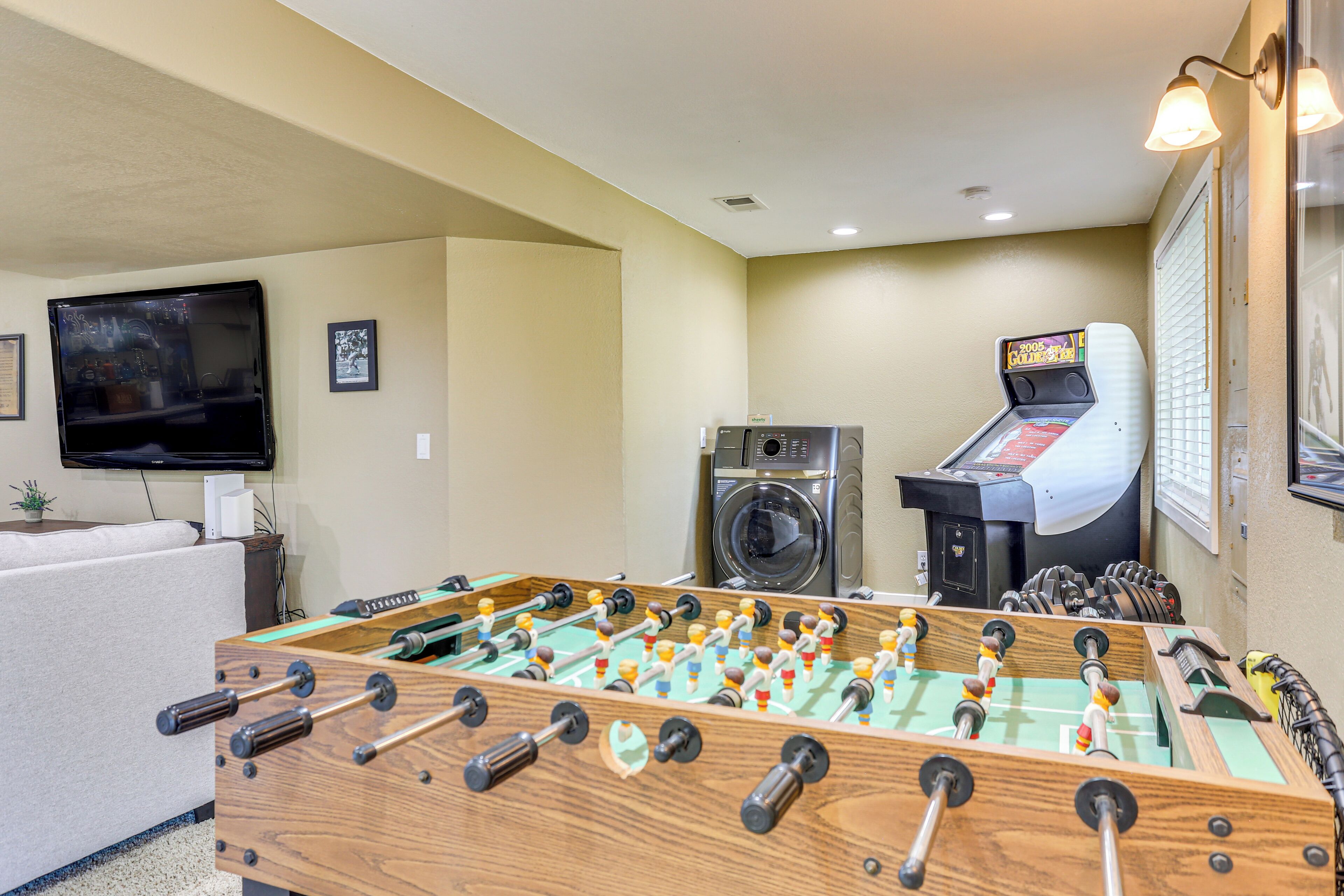 A room with a foosball table, a washing machine, and a coin-operated game machine.
