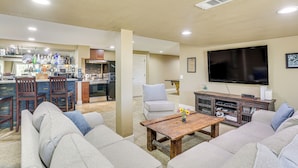 Una sala de estar con sofá, una mesa de centro, televisión y una cocina al fondo.