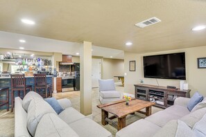 Una sala de estar con sofá, una mesa de centro, televisión y una cocina al fondo.