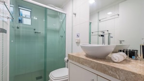 Un baño moderno con ducha envuelta en vidrio, un lavabo blanco y un espejo grande.