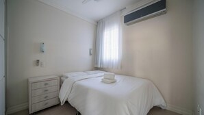 A bedroom with a bed, a nightstand, a dresser, a ceiling fan, and an air conditioning unit. - Cozy 3BR apt W/balcony sea View Cet1702 (Balneário Camboriú)