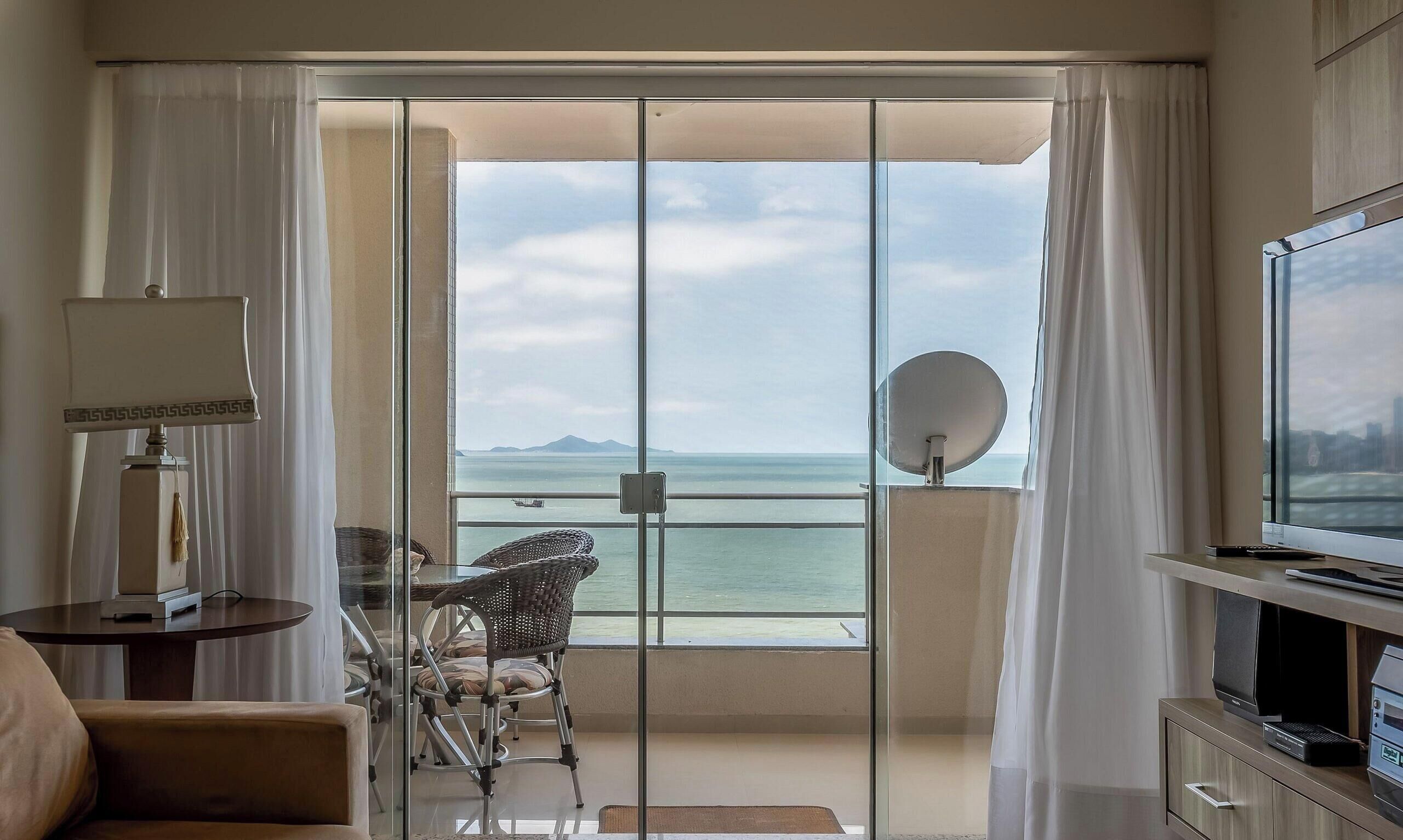 A hotel room with a balcony, a television, a lamp, and a chair.