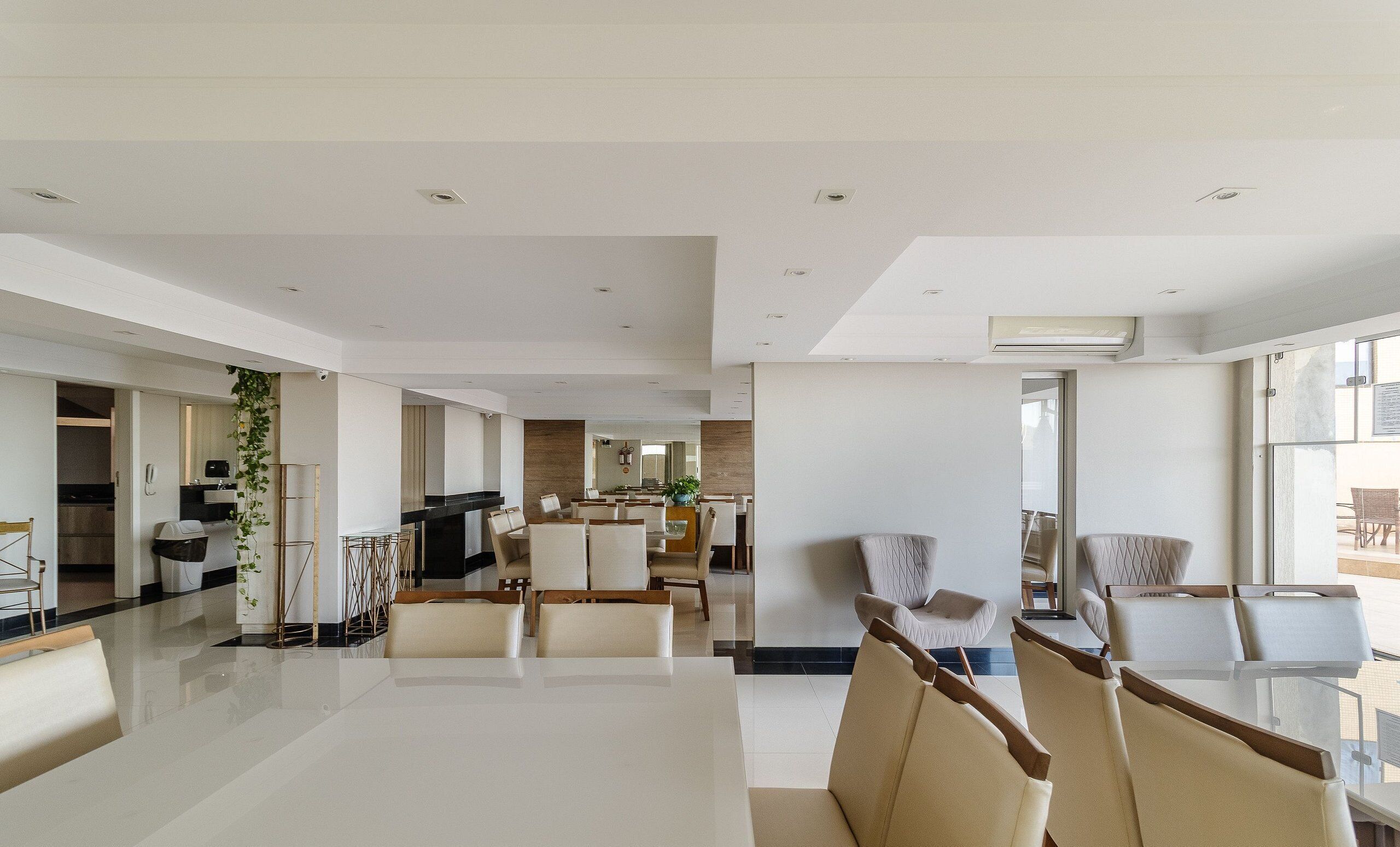 A spacious, modern living area with a large dining table, comfortable seating, and a kitchen in the background.