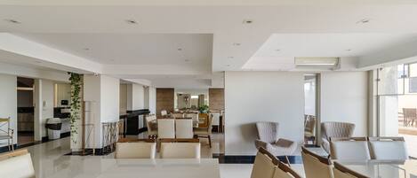 A spacious, modern living area with a large dining table, comfortable seating, and a kitchen in the background.