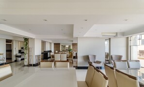 A spacious, modern living area with a large dining table, comfortable seating, and a kitchen in the background. - Cozy 3BR apt W/balcony sea View Cet1702 (Balneário Camboriú)