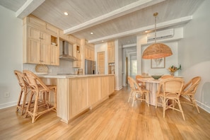 A spacious kitchen with wooden cabinets, a central island, and wicker chairs.