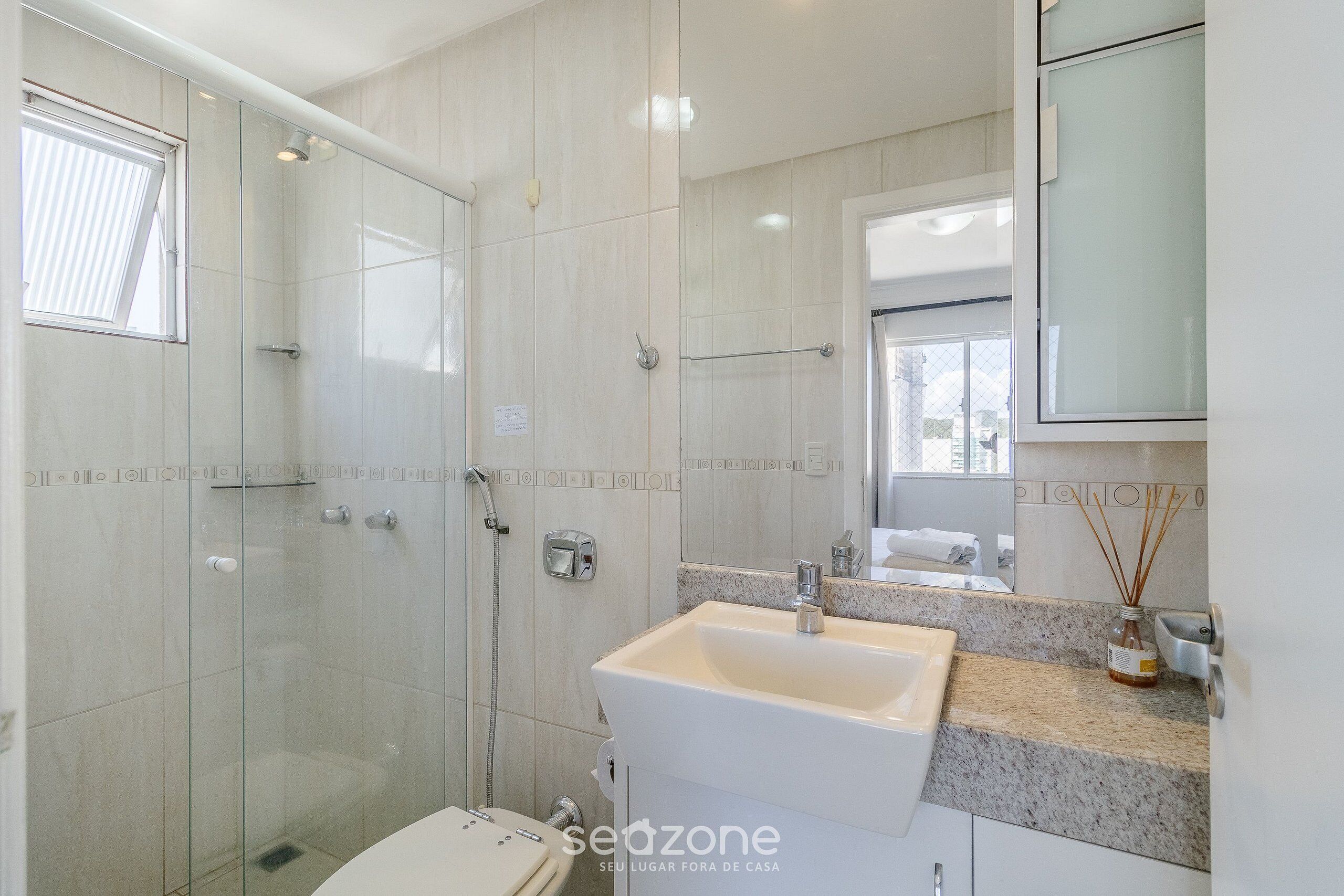 Un baño moderno con cabina de ducha de vidrio, un lavabo con encimera de mármol y un espejo sobre el lavabo.