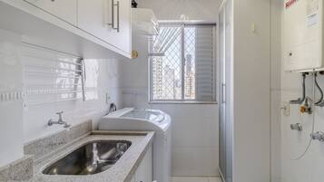 Cuina moderna amb taulell de granat, rentatalla d'acer inoxidable i armaris blancs.