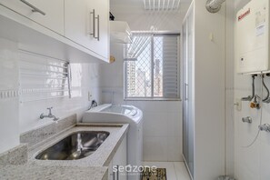 A modern kitchen with a granite countertop, stainless steel sink, and white cabinetry. - Hermoso Apt la Orla de Balneário Camboriú CET1604 (Balneário Camboriú)