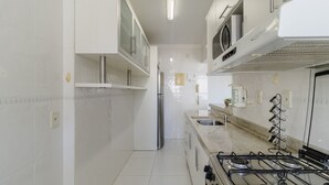 A modern kitchen with white cabinetry, a stainless steel refrigerator, a gas stove, and a built-in oven.