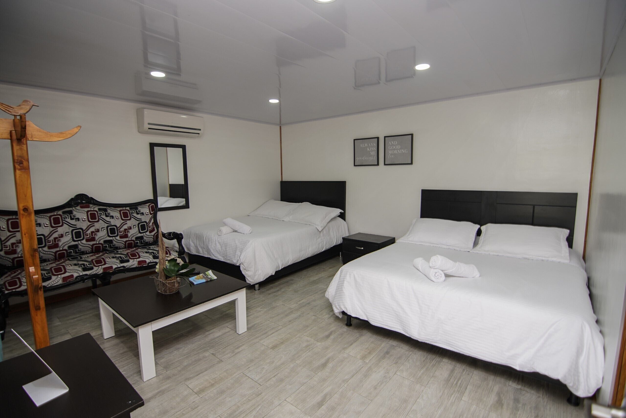 A hotel room with two beds, a sofa, a small table, and a wooden chair.