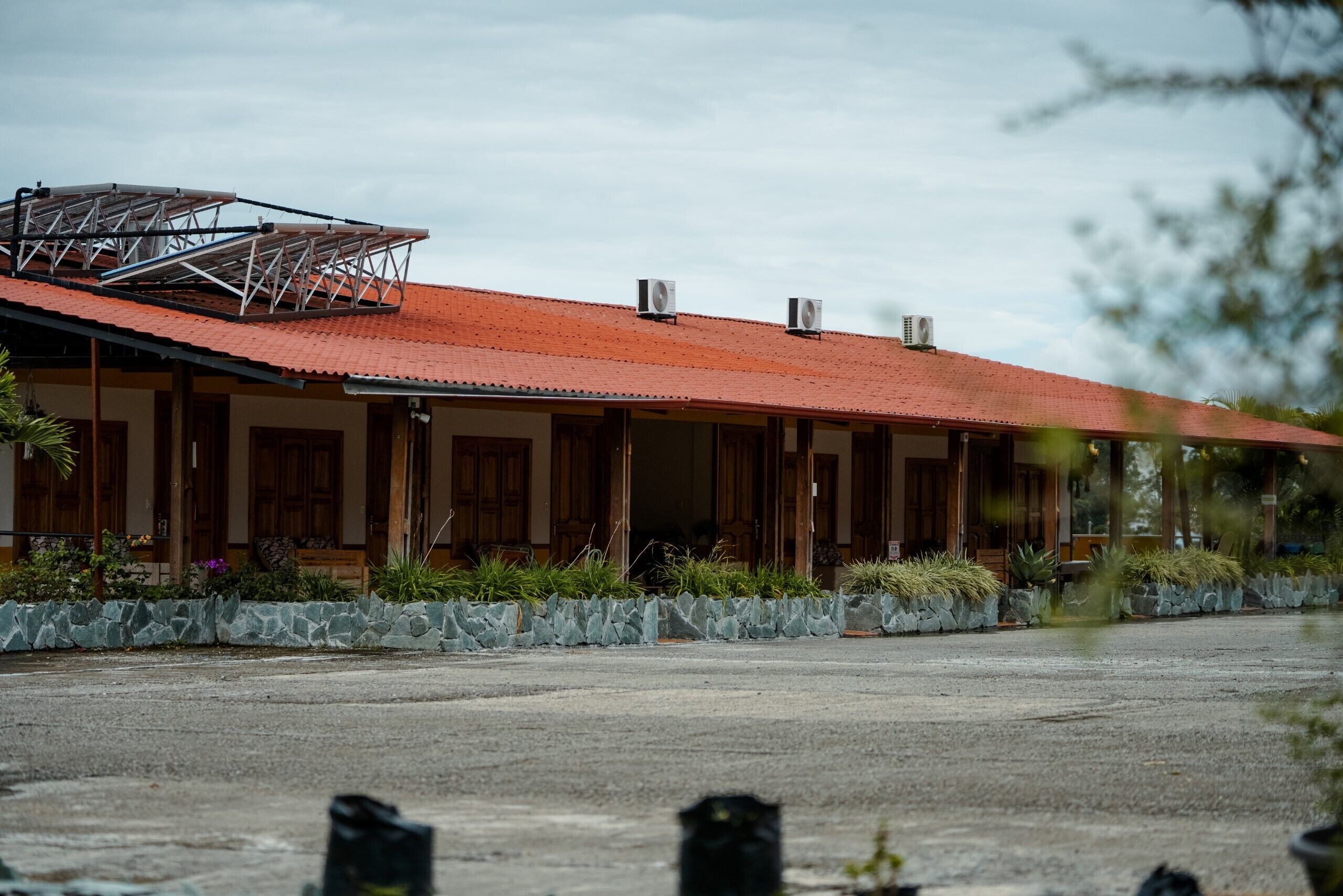 A building with a red roof, stone walls, and wooden doors.