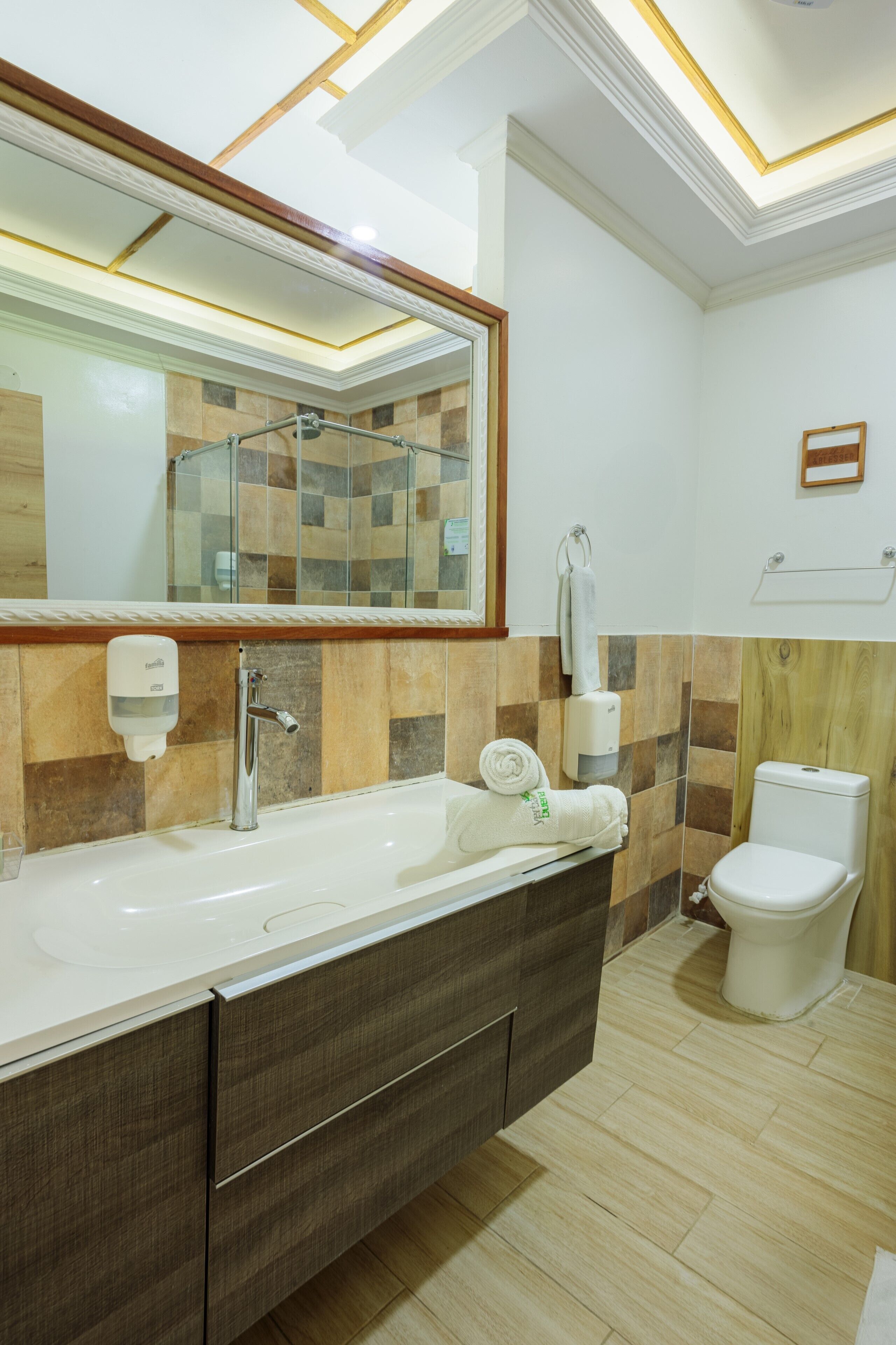 Un baño moderno con un espejo grande, un lavamanos, un inodoro y un perchero para toallas.
