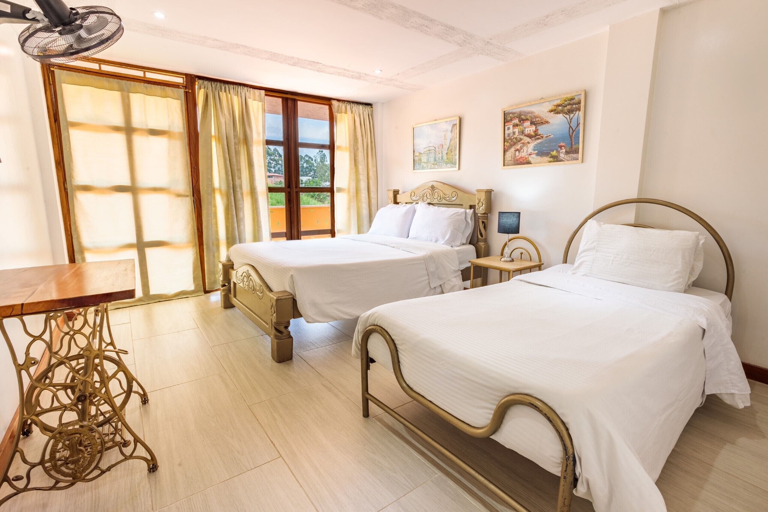 A hotel room with two beds, a sewing machine, and a table.