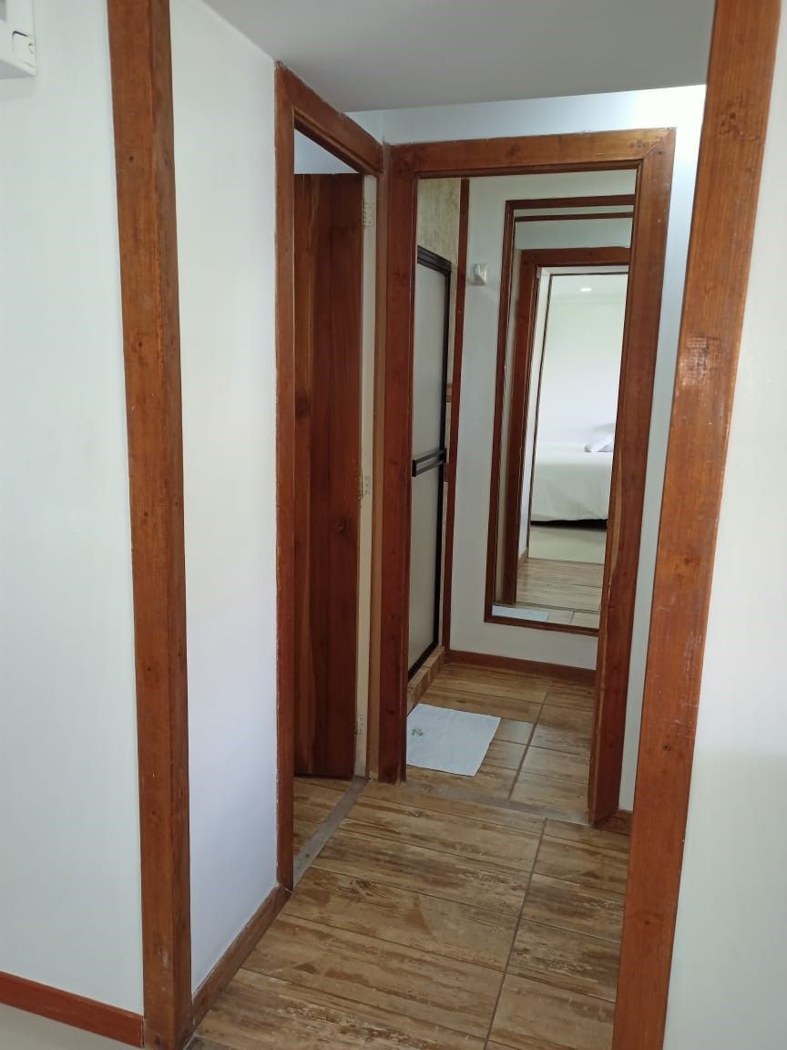 A narrow hallway with wooden door frames and a tiled floor.