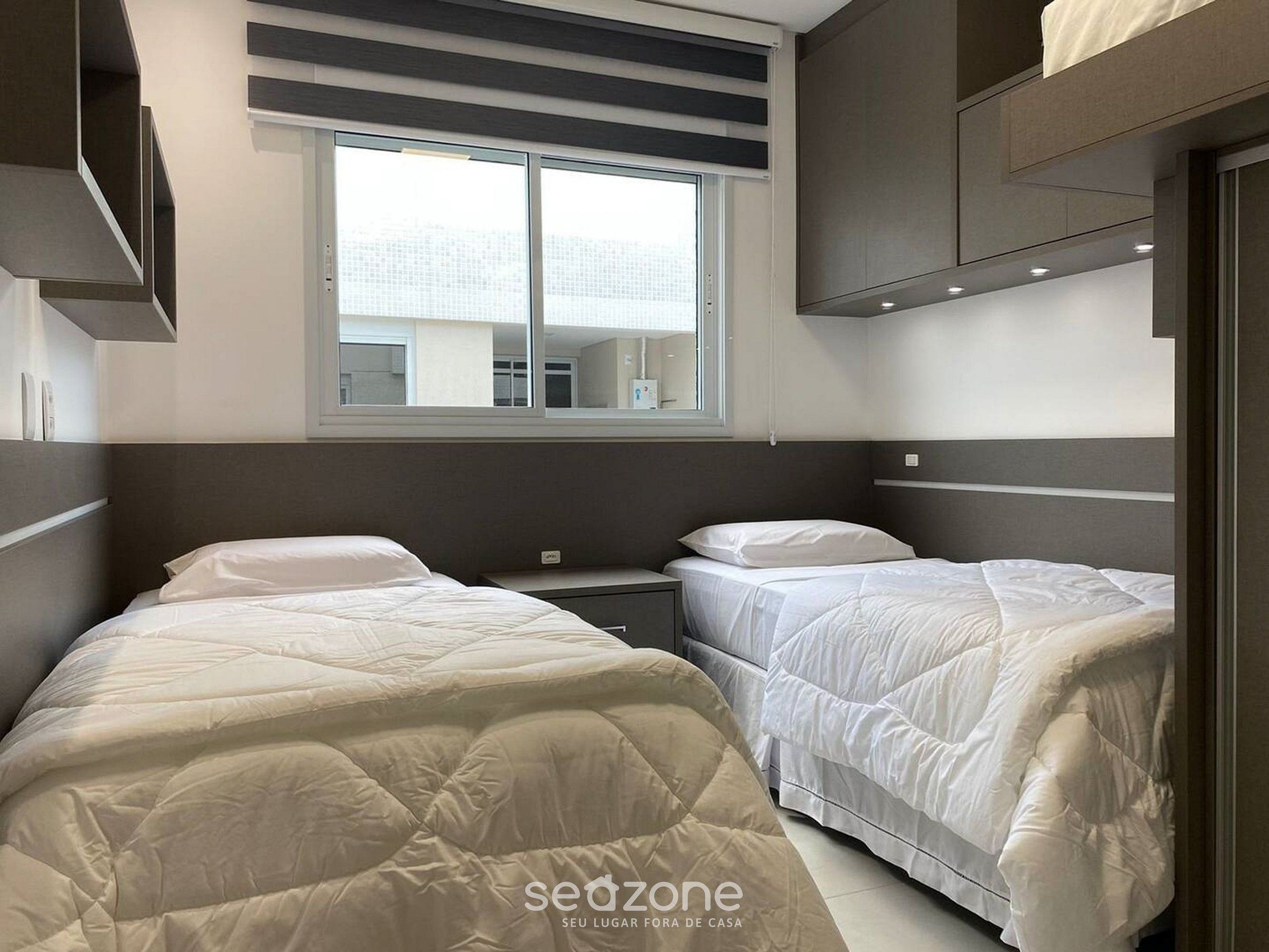 Una habitación de hotel moderna con dos camas, un ventanal grande y vistas a la ciudad.