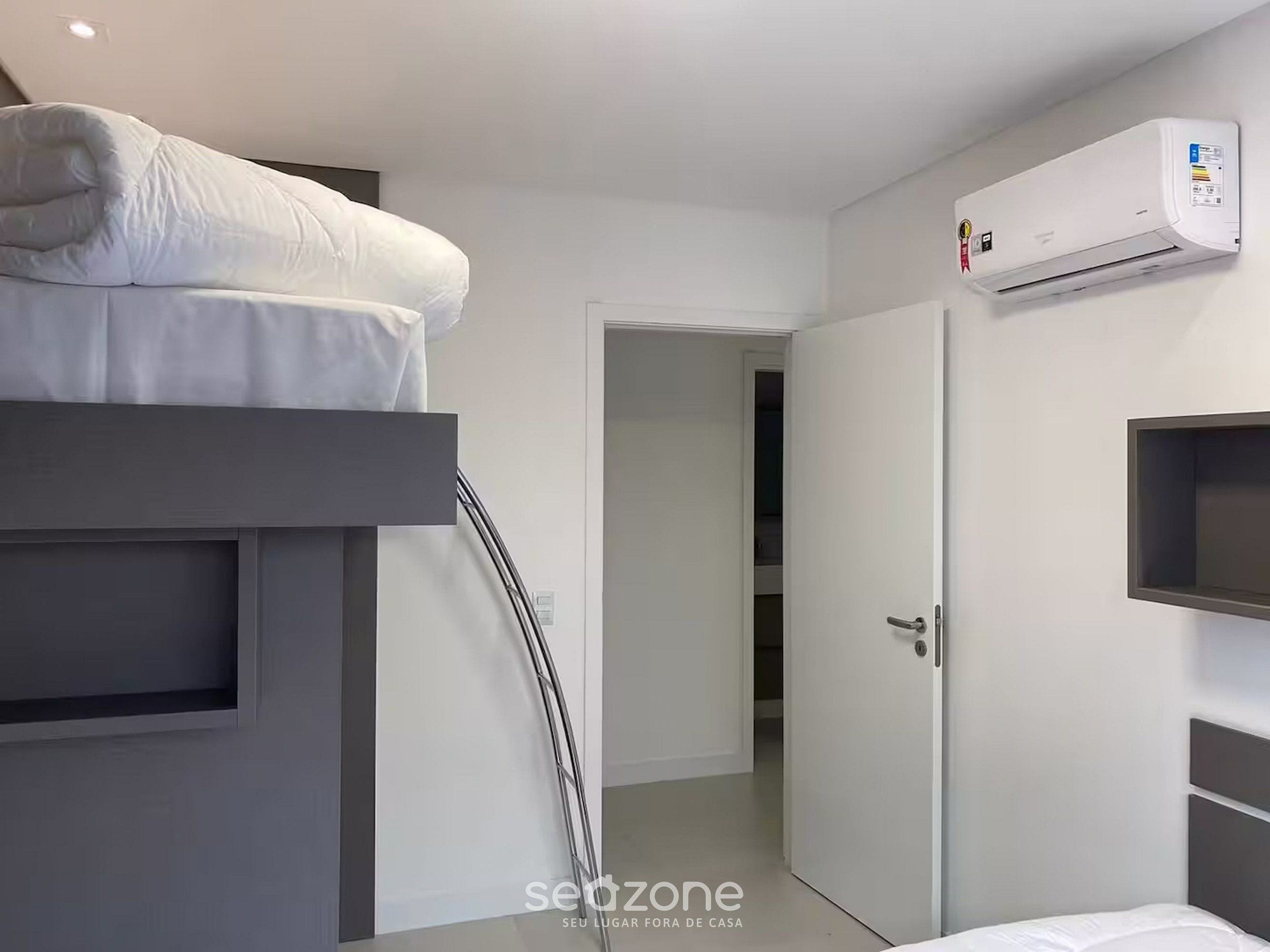 A modern hotel room with a bunk bed, a built-in wardrobe, and a wall-mounted air conditioning unit.