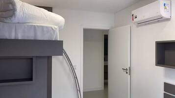 A modern hotel room with a bunk bed, a built-in wardrobe, and a wall-mounted air conditioning unit.