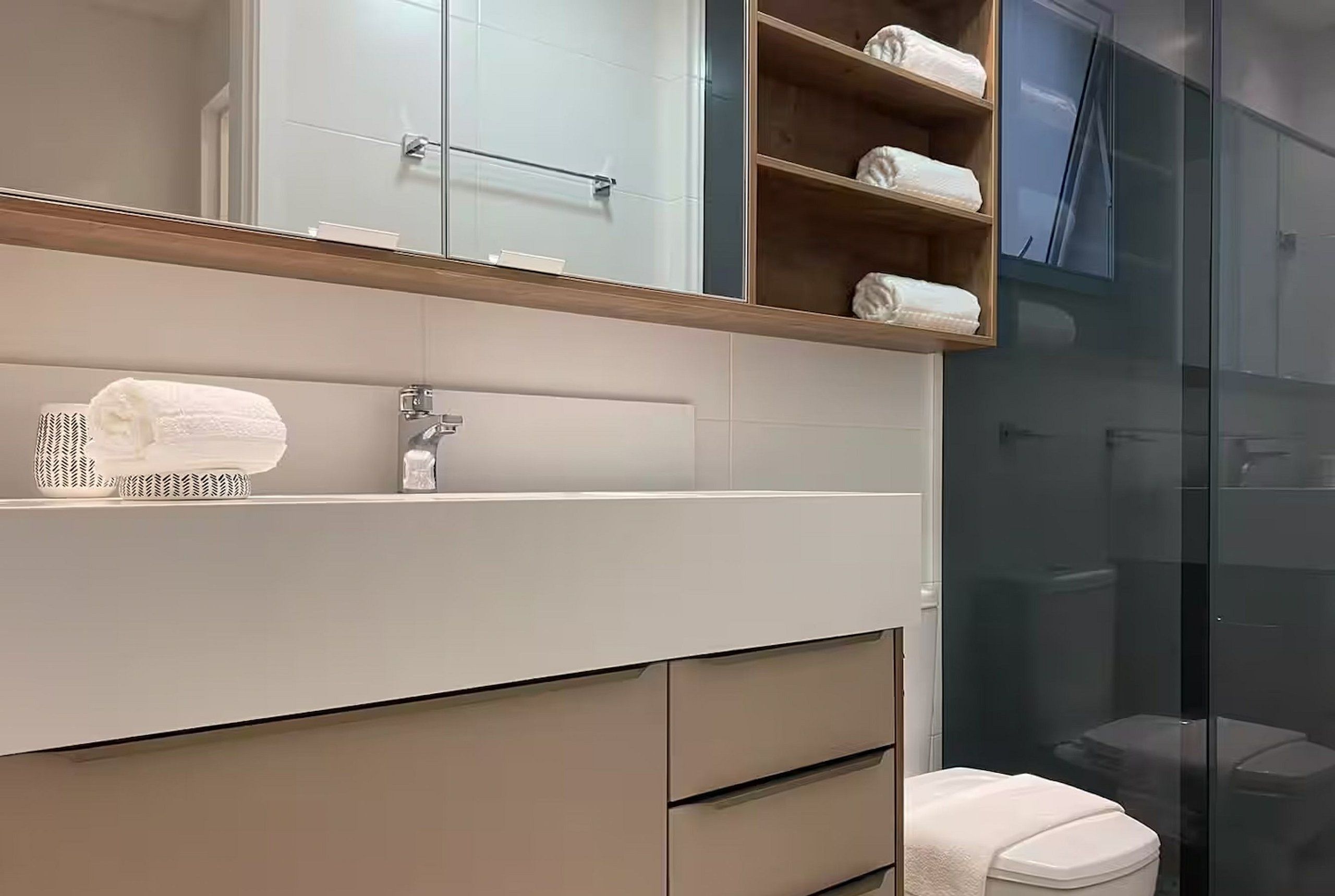 Un baño moderno con un espejo grande, un perchero para toallas y una cabina de ducha con paredes de vidrio.