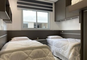 Una habitación de hotel moderna con dos camas, un ventanal grande y vistas a la ciudad.