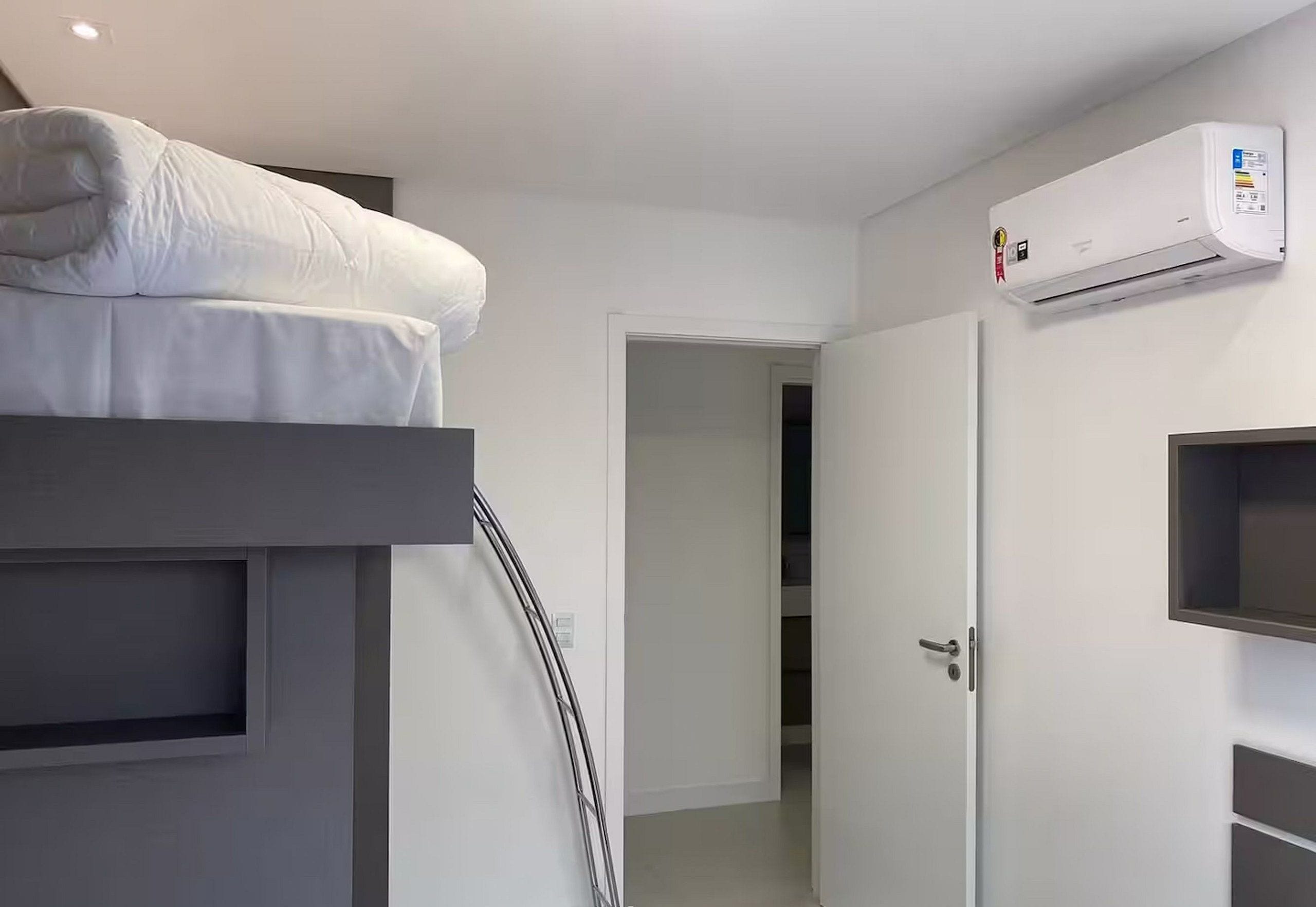 A modern hotel room with a bunk bed, a built-in wardrobe, and a wall-mounted air conditioning unit.