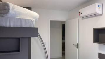 A modern hotel room with a bunk bed, a built-in wardrobe, and a wall-mounted air conditioning unit.
