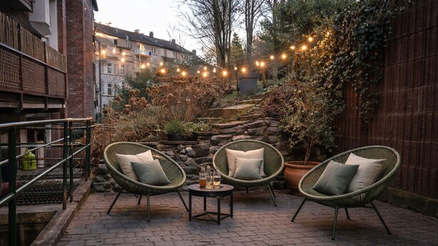 An outdoor patio with wicker chairs, a small table, and string lights.
