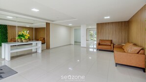 Un amplio y moderno salón con una consola blanca, un sofá de cuero marrón y una mesa de centro de vidrio.