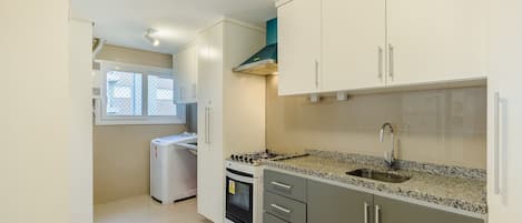 A kitchen with white cabinets, a granite countertop, a stove, and a sink.