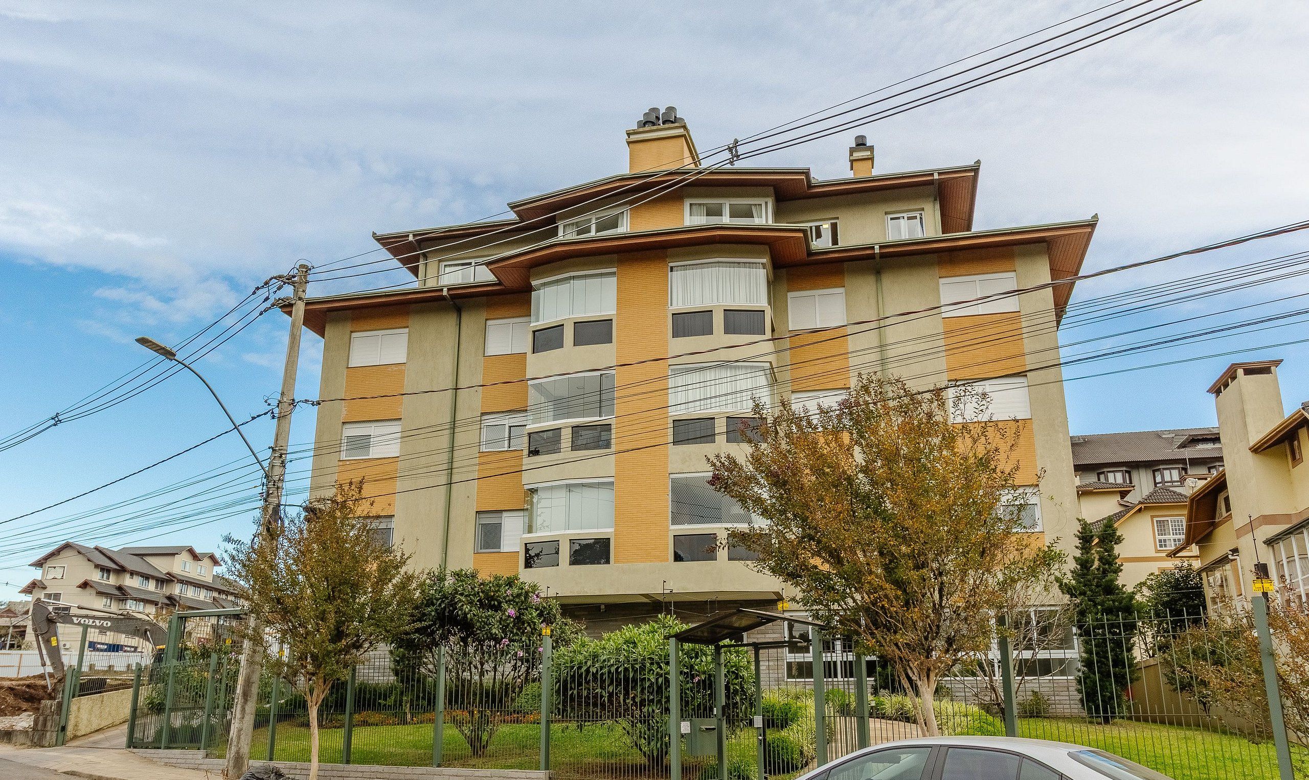 A multi-story residential building with a flat roof, multiple balconies, and a gated entrance.